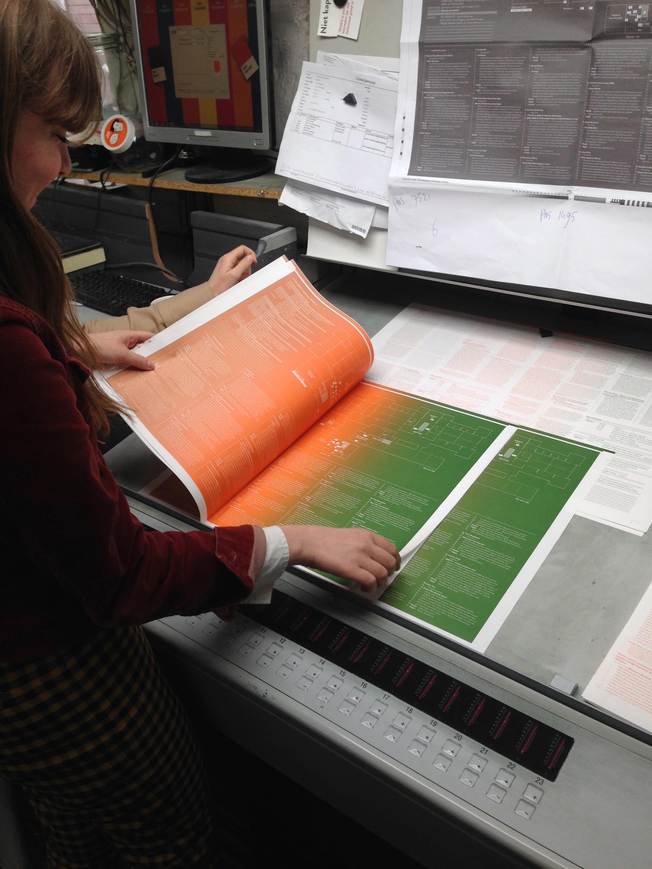 Person holding a sample of a printed sheet for a book at the printing house